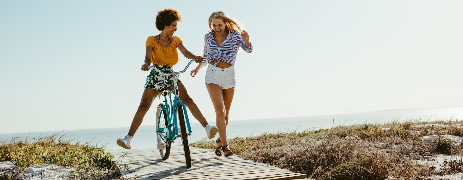 two women with a bike on a beach